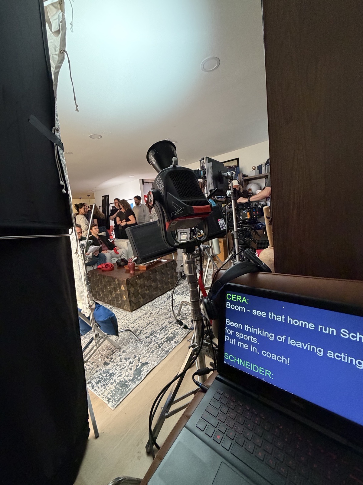 Teleprompter monitor beside a cinema camera on a scripted scene set
