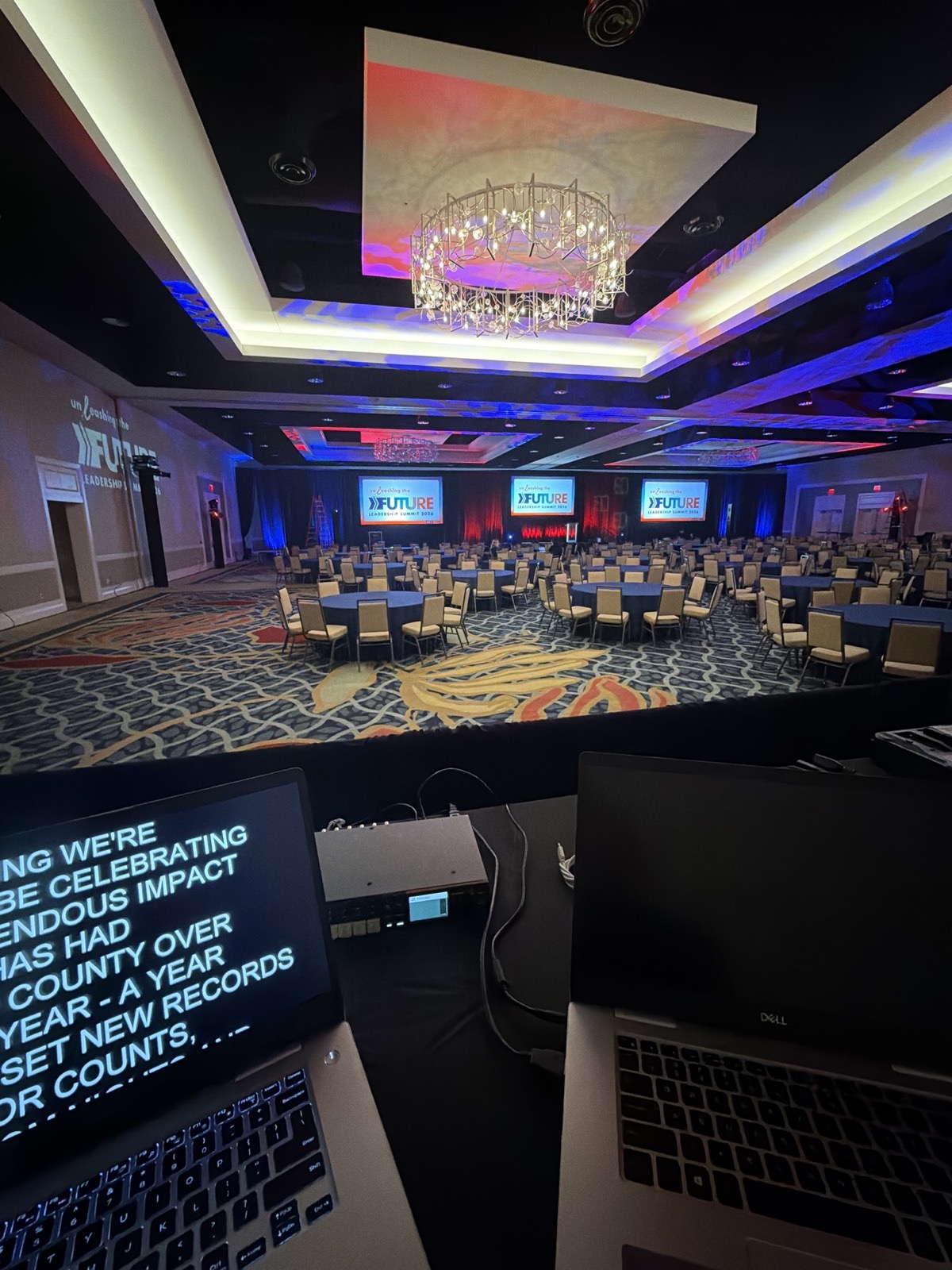 Operator station with teleprompter laptops facing a ballroom stage